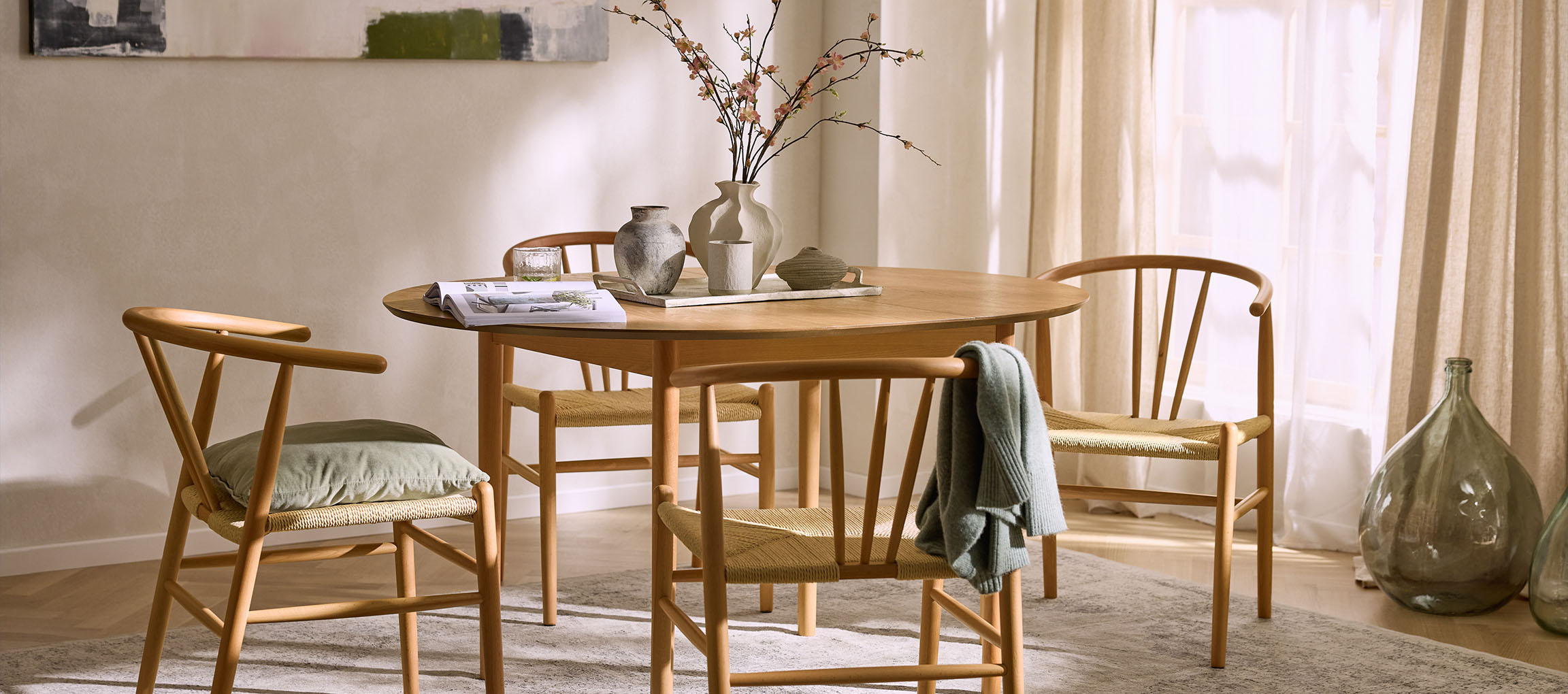 Étkező kerek fa asztallal, fa székekkel, kötélülésekkel és dekoratív vázákkal.