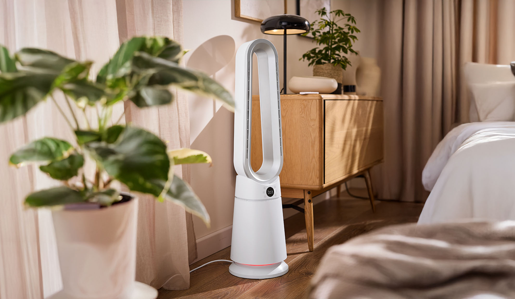 Fehér toronyventilátor modern hálószobában, növényekkel és fabútorokkal.