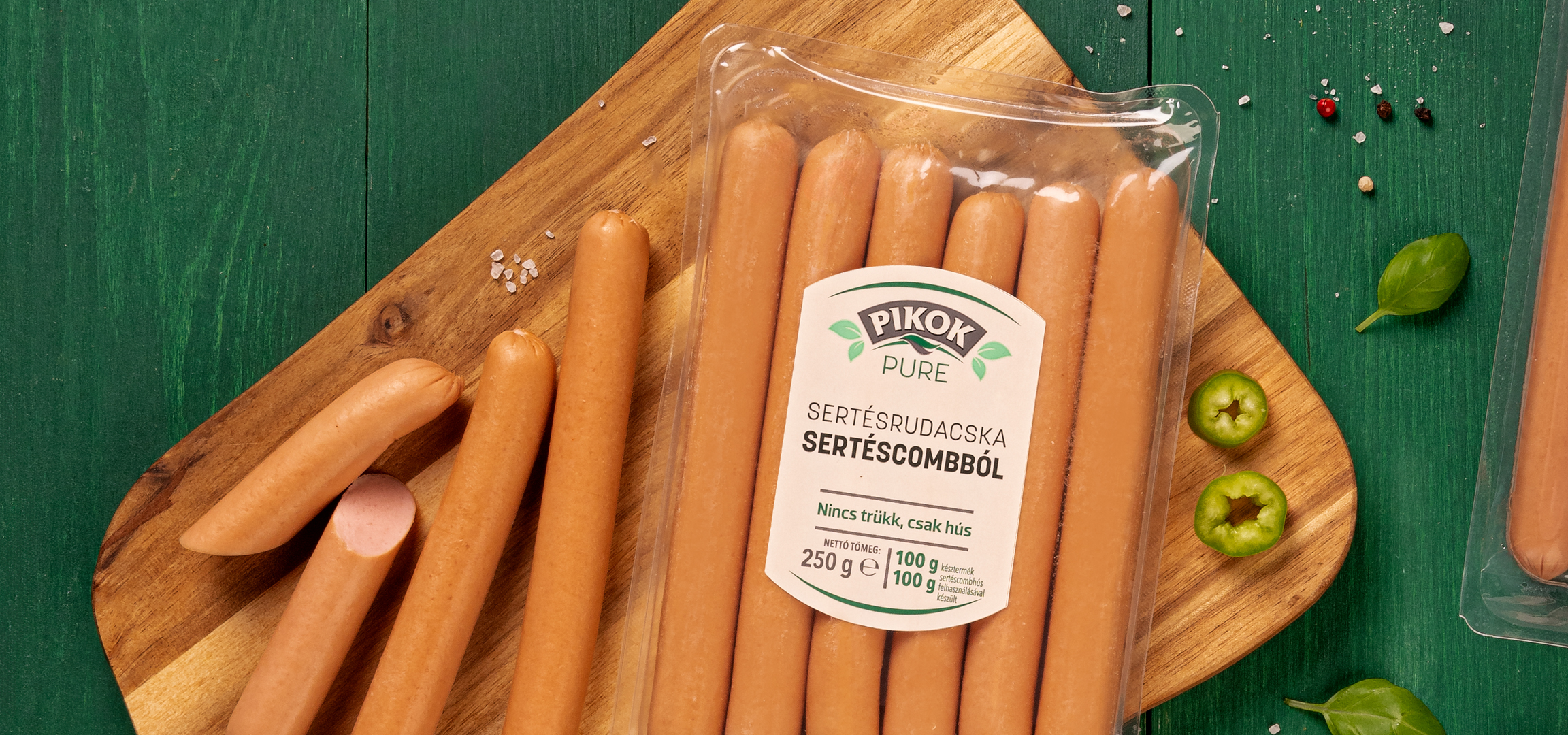 Pikok Pure sertésrudacskák csomagolásban, vágódeszkán, zöld alapon.