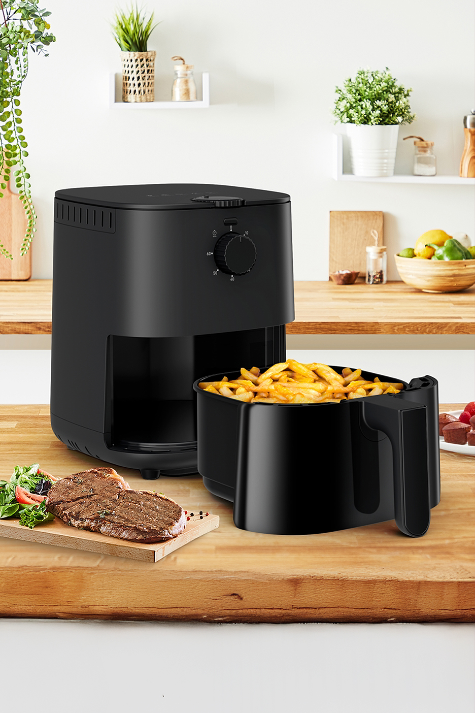 Fekete forrólevegős fritőz sült krumplival és steakkel egy konyhapulton.