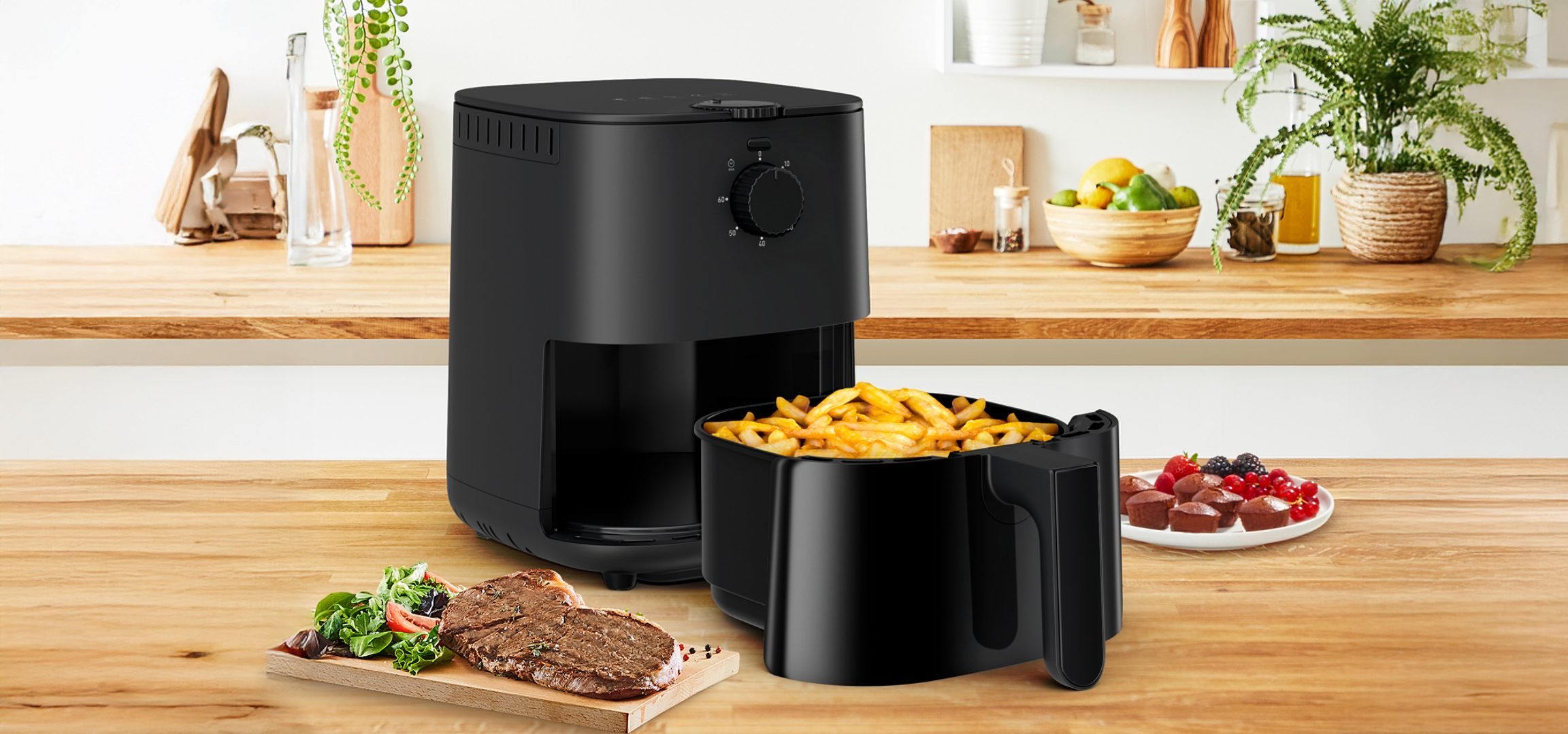 Fekete forrólevegős fritőz sült krumplival, steakkel és desszerttel egy konyhapulton.