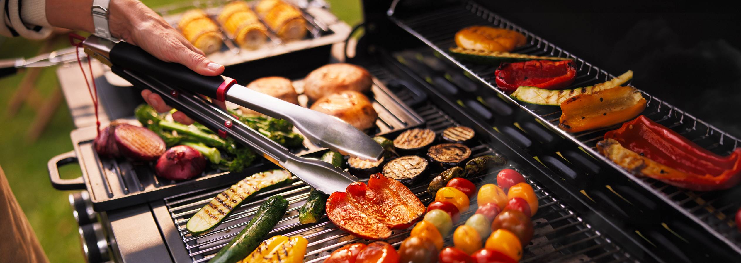 Sütés közben lévő zöldségek és húsok egy grillezőn.