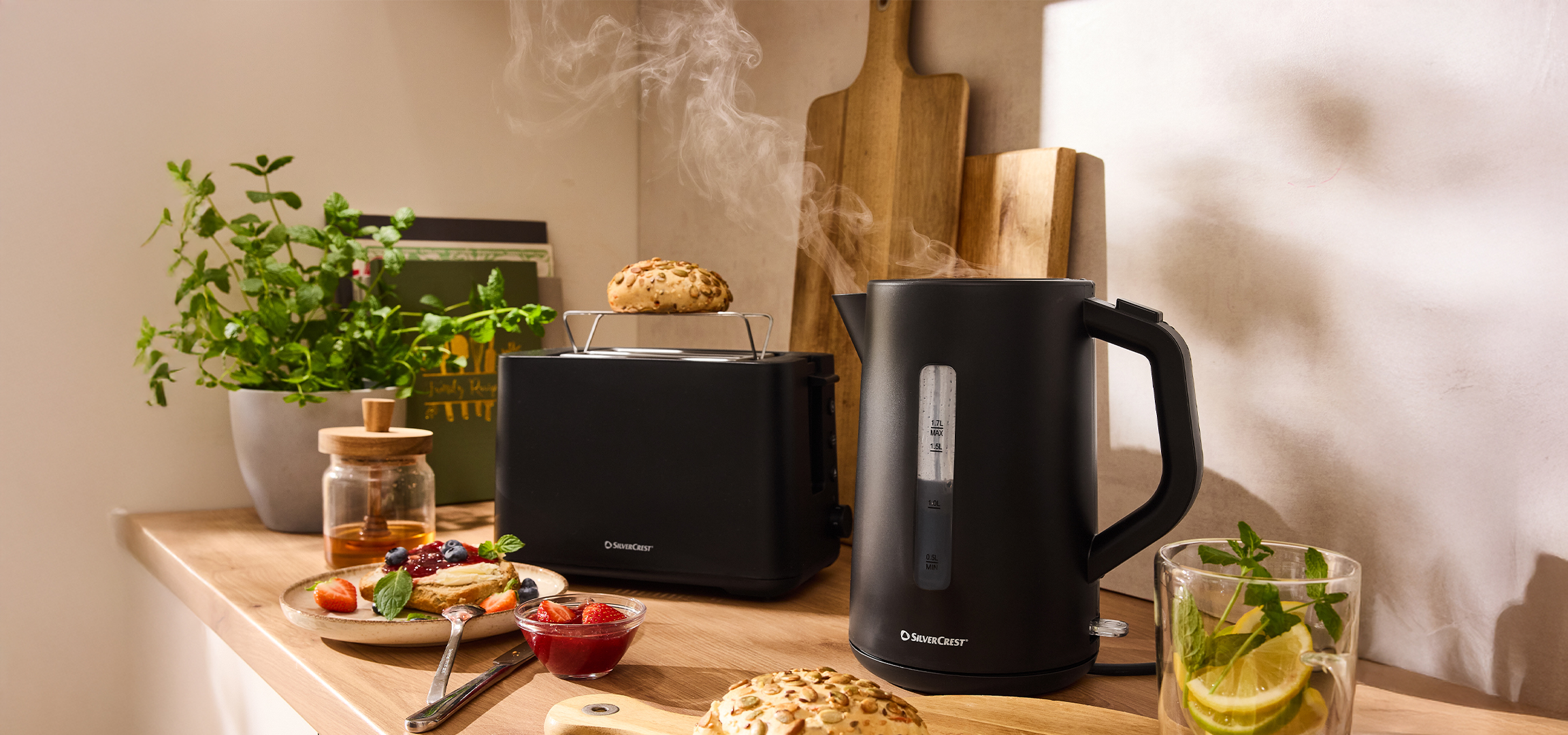 SilverCrest fekete vízforraló és kenyérpirító reggelivel egy konyhapulton.