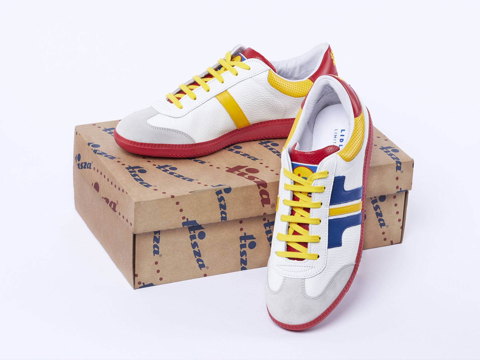 Lidl márkájú, fehér, piros, sárga és kék színű Tisza cipők egy barna dobozon.