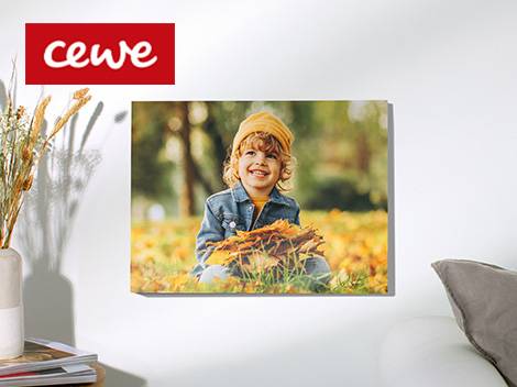 Egy CEWE márkájú, falra szerelt vászonkép egy mosolygó gyermekről, aki őszi leveleket tart.