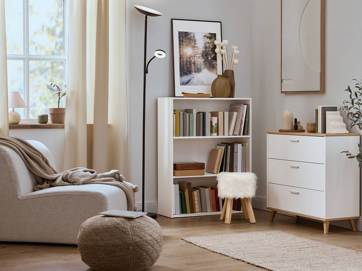 Hangulatos nappali fotellel, könyvespolccal és komóddal semleges színekben.