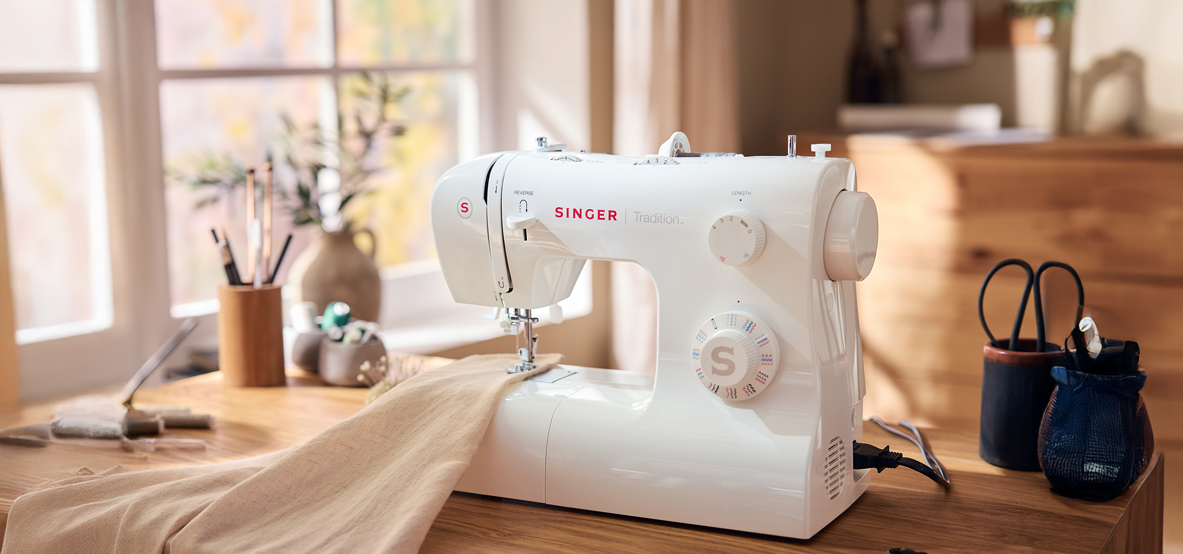 Singer varrógép egy fa asztalon, otthoni környezetben, varrásra készen.