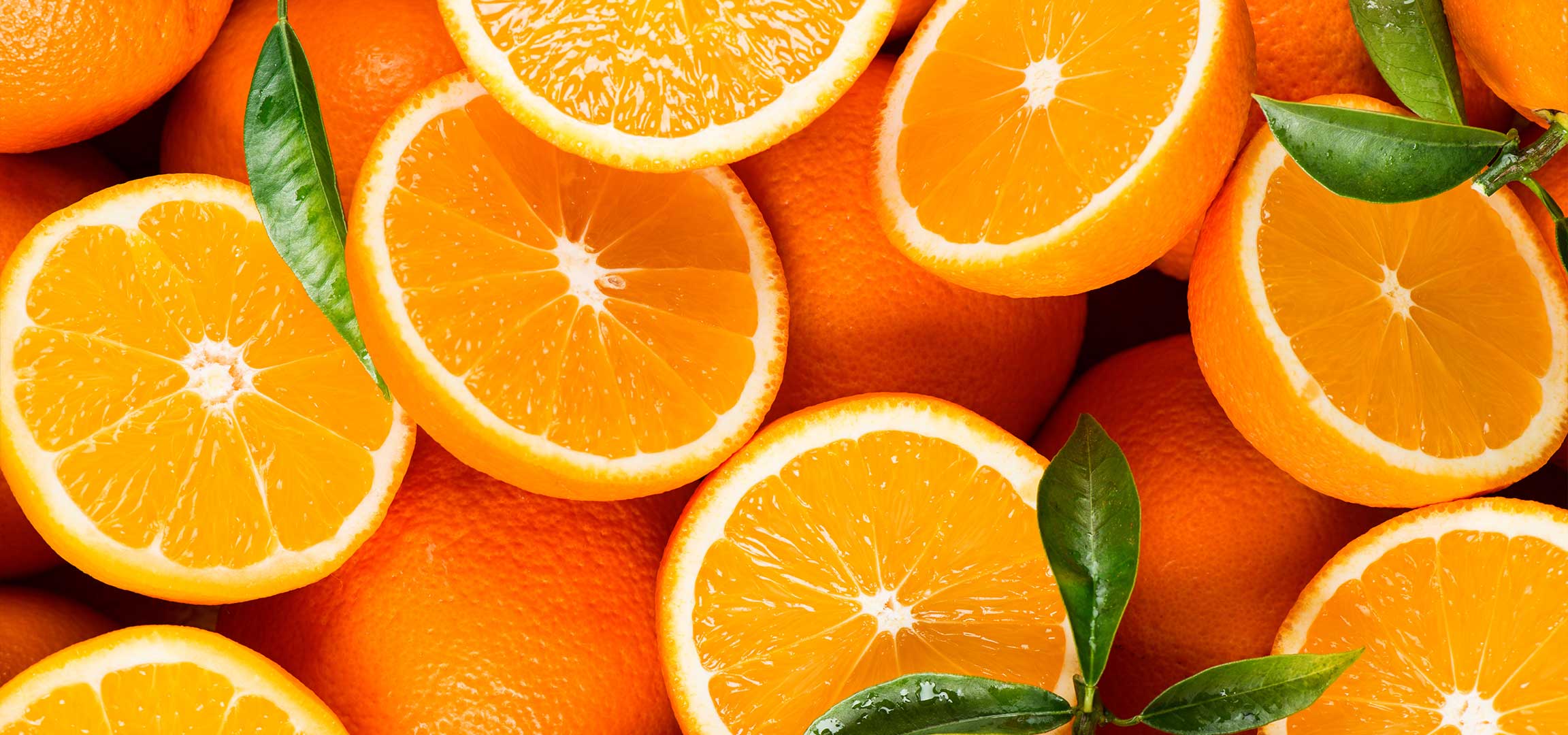 Közeli felvétel egy halom érett narancsról, az egyik félbevágva.