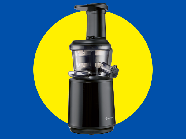 Fekete lassú préselésű gyümölcscentrifuga sárga kör előtt, kék háttérrel.