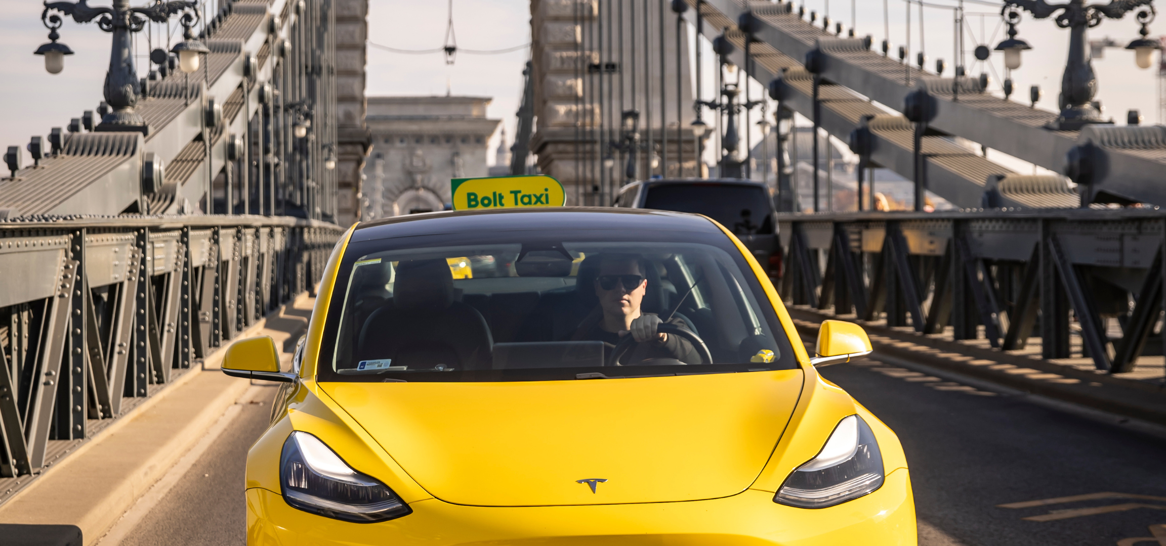 Sárga és zöld taxitábla a tetőn, „Bolt Taxi” felirattal.