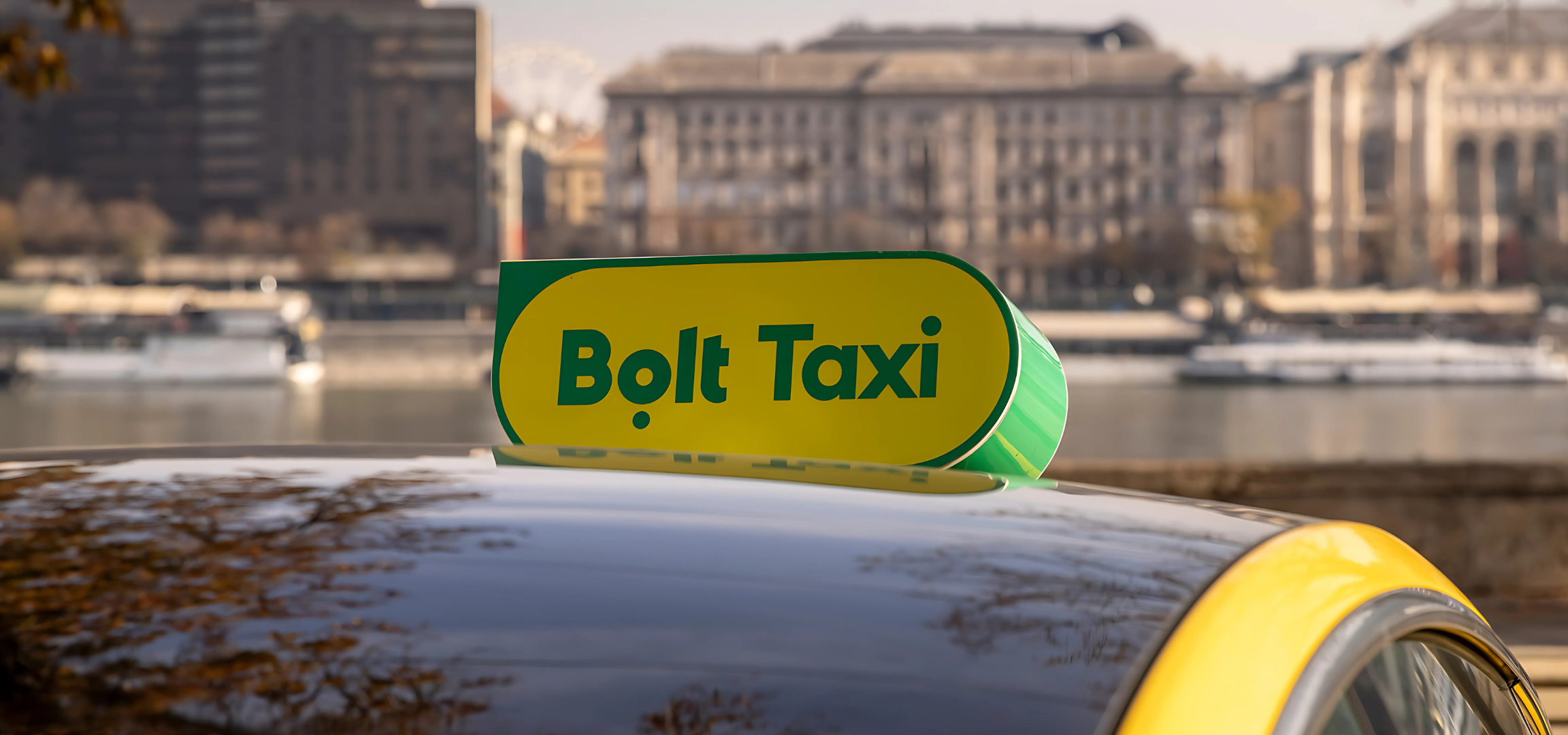 Fiatal nő áll egy sárga taxival egy városi utcán.