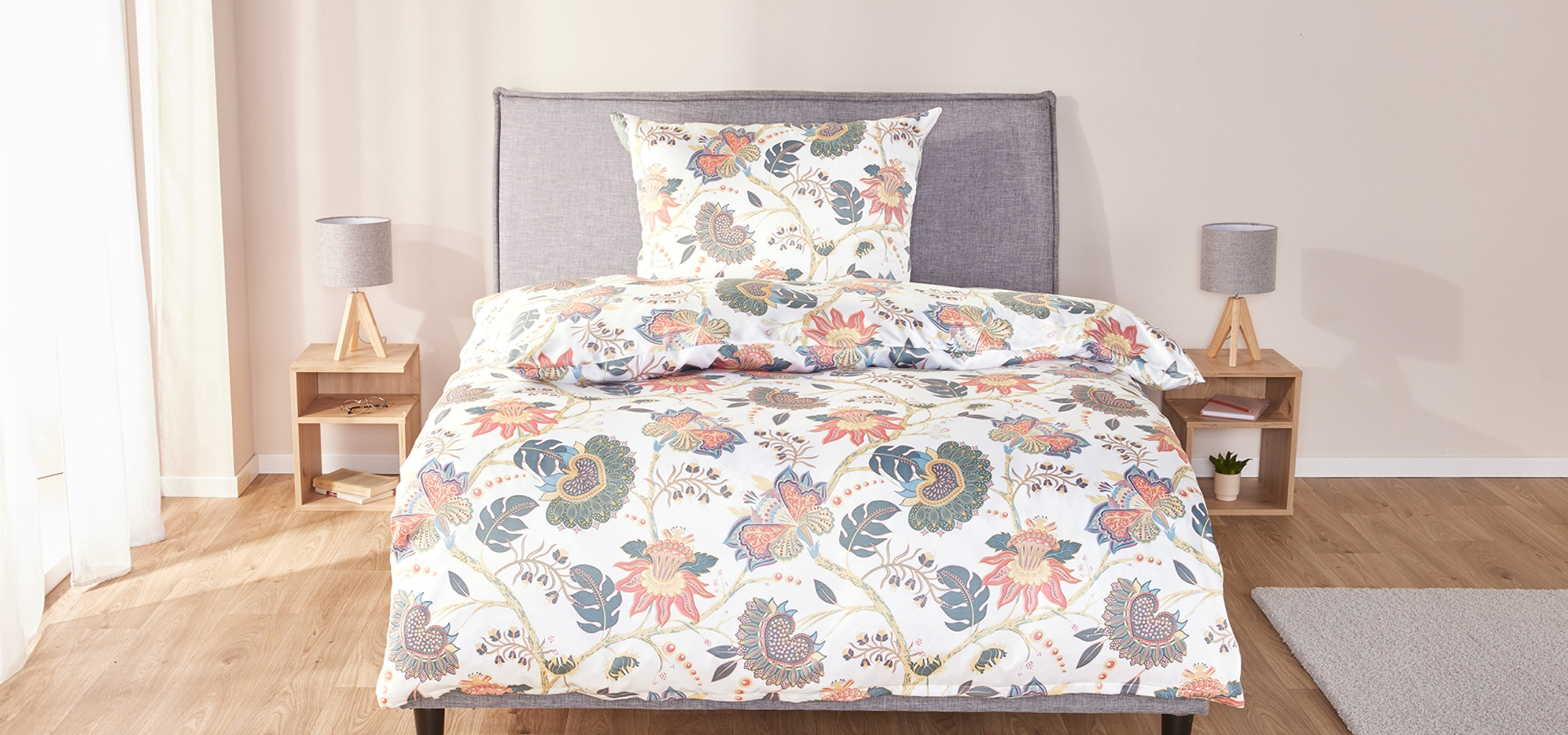 Hálószoba virágmintás ágyneművel, éjjeli szekrényekkel és lámpákkal.